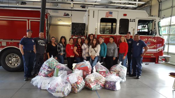Women and Firefighters in front of Firetruck with bags of wrapped toys